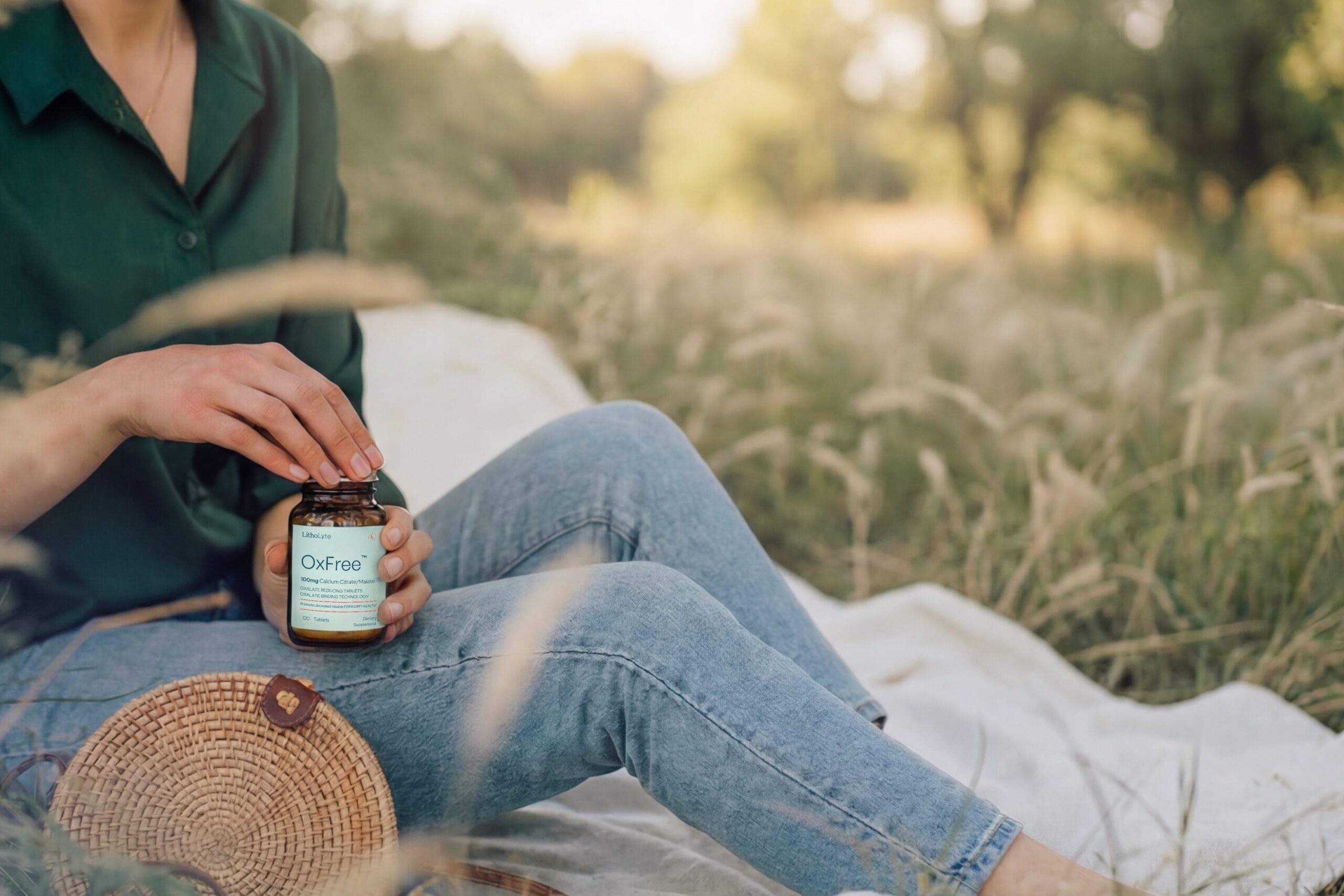 Woman holding an OxFree bottle in a sunlit field